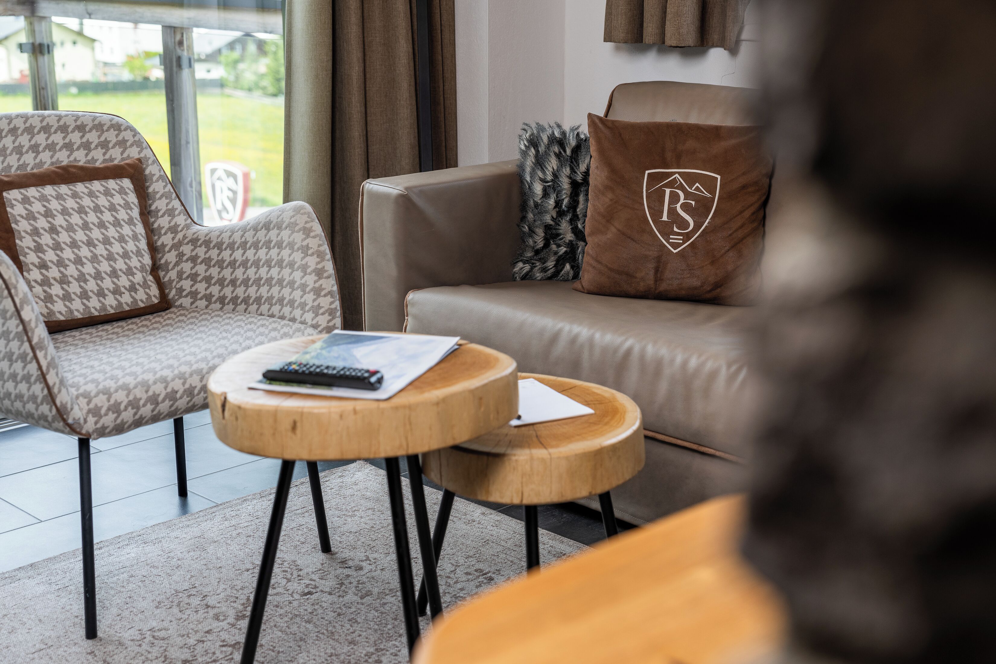 A modern living room with a sofa, armchair, and round wooden tables.