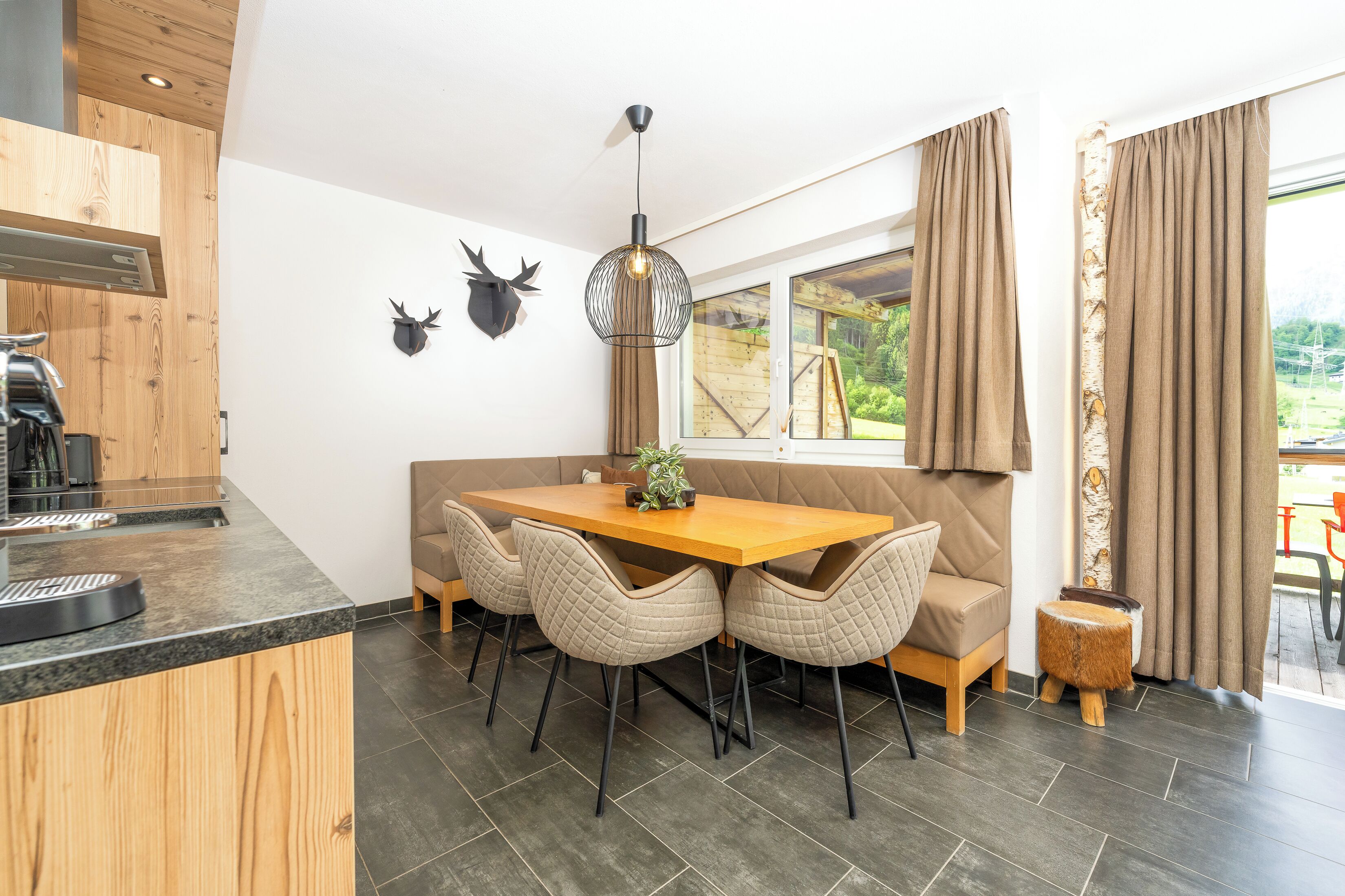 A modern kitchen with a wooden countertop, a dining table with four chairs, and a hanging light fixture.