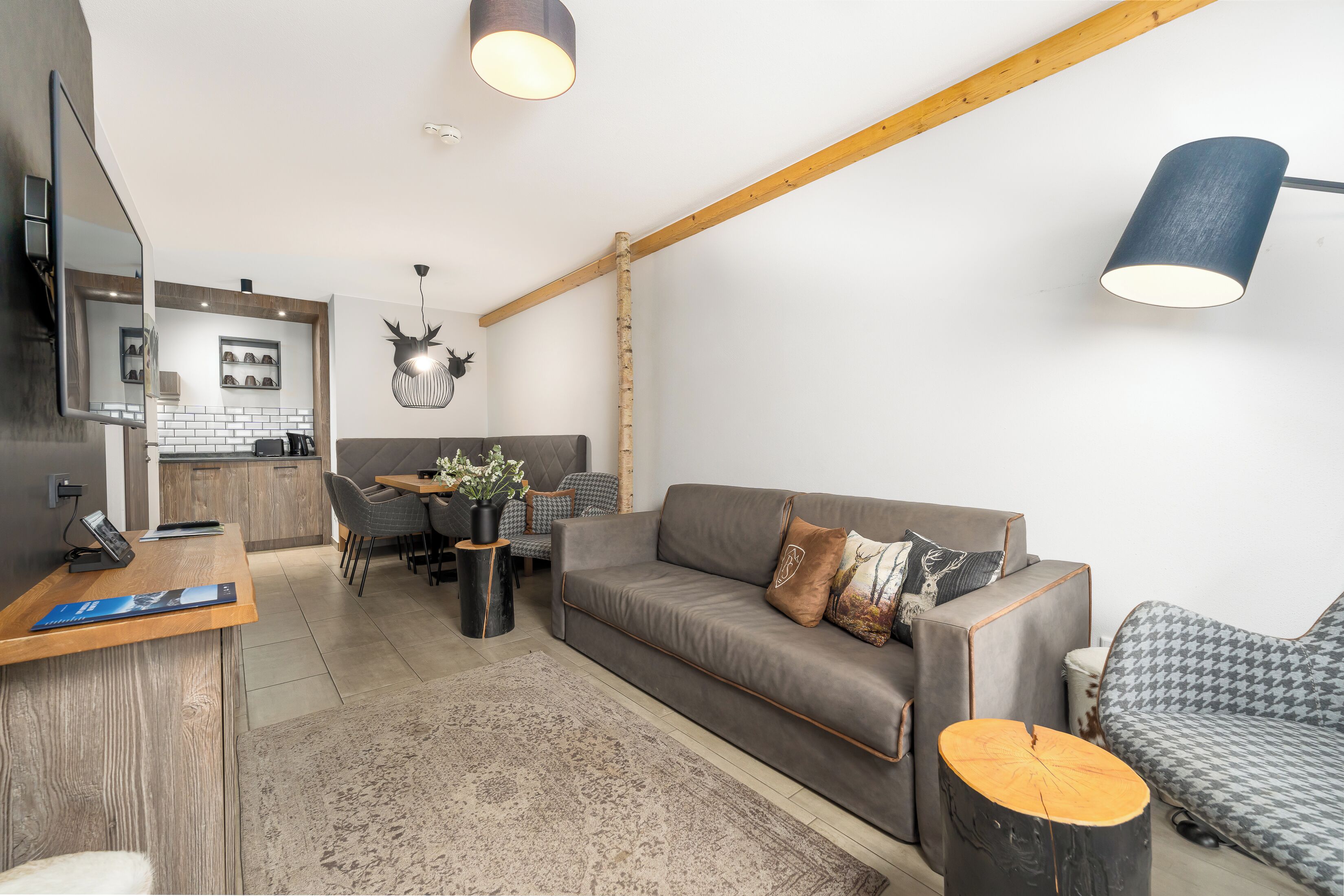 A modern living room with a grey sofa, wooden coffee table, and a dining area with a chair and table.