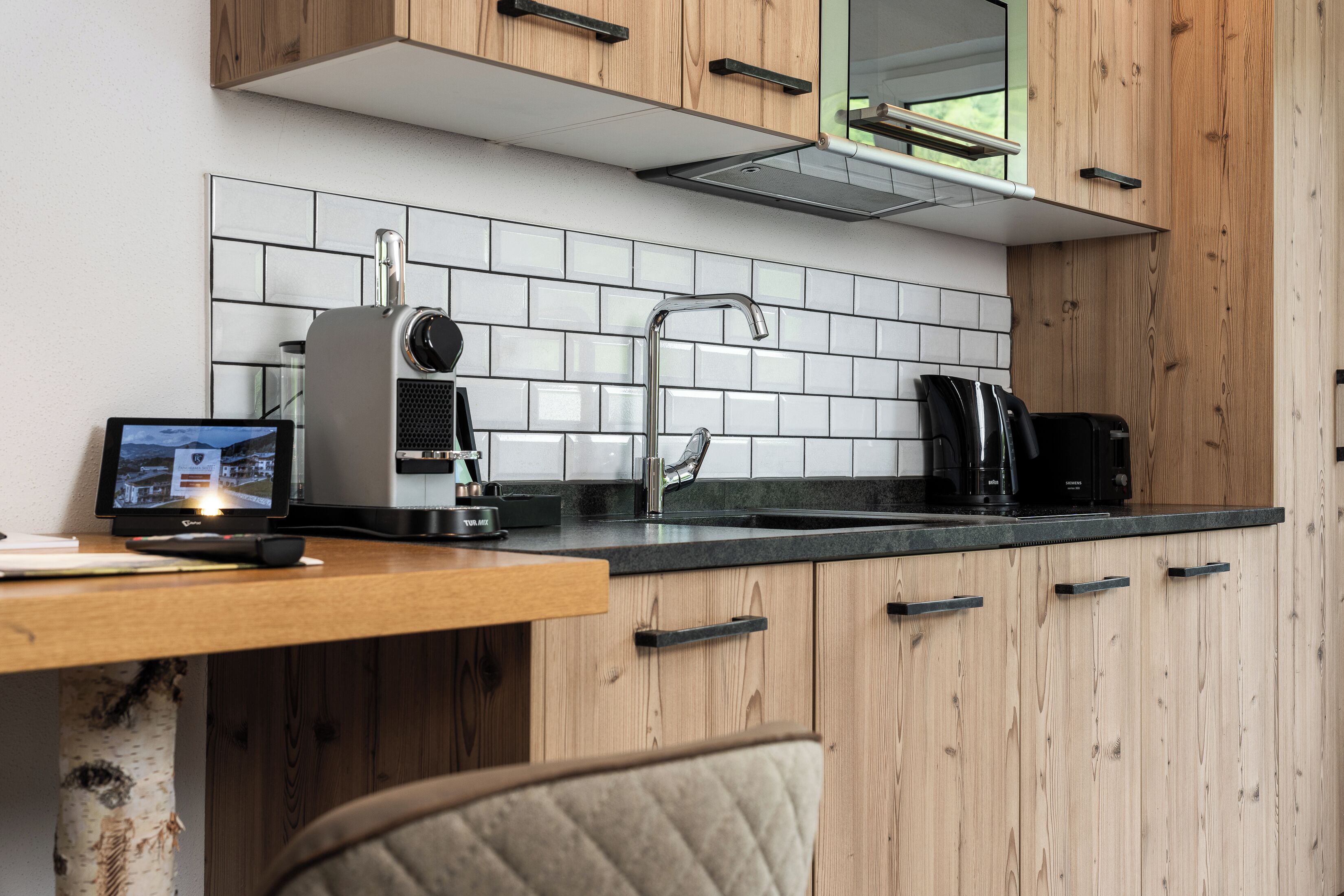 Une cuisine moderne avec des meubles en bois, un plan de travail noir et une cuisinière intégrée.