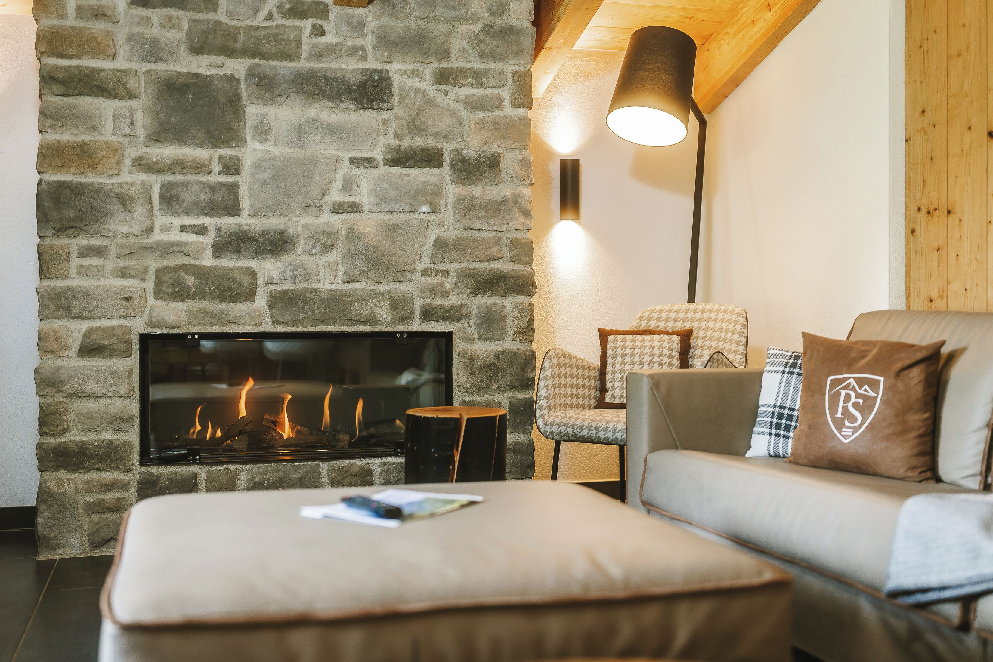 A cozy living room with a stone fireplace, a sofa, and a lamp.