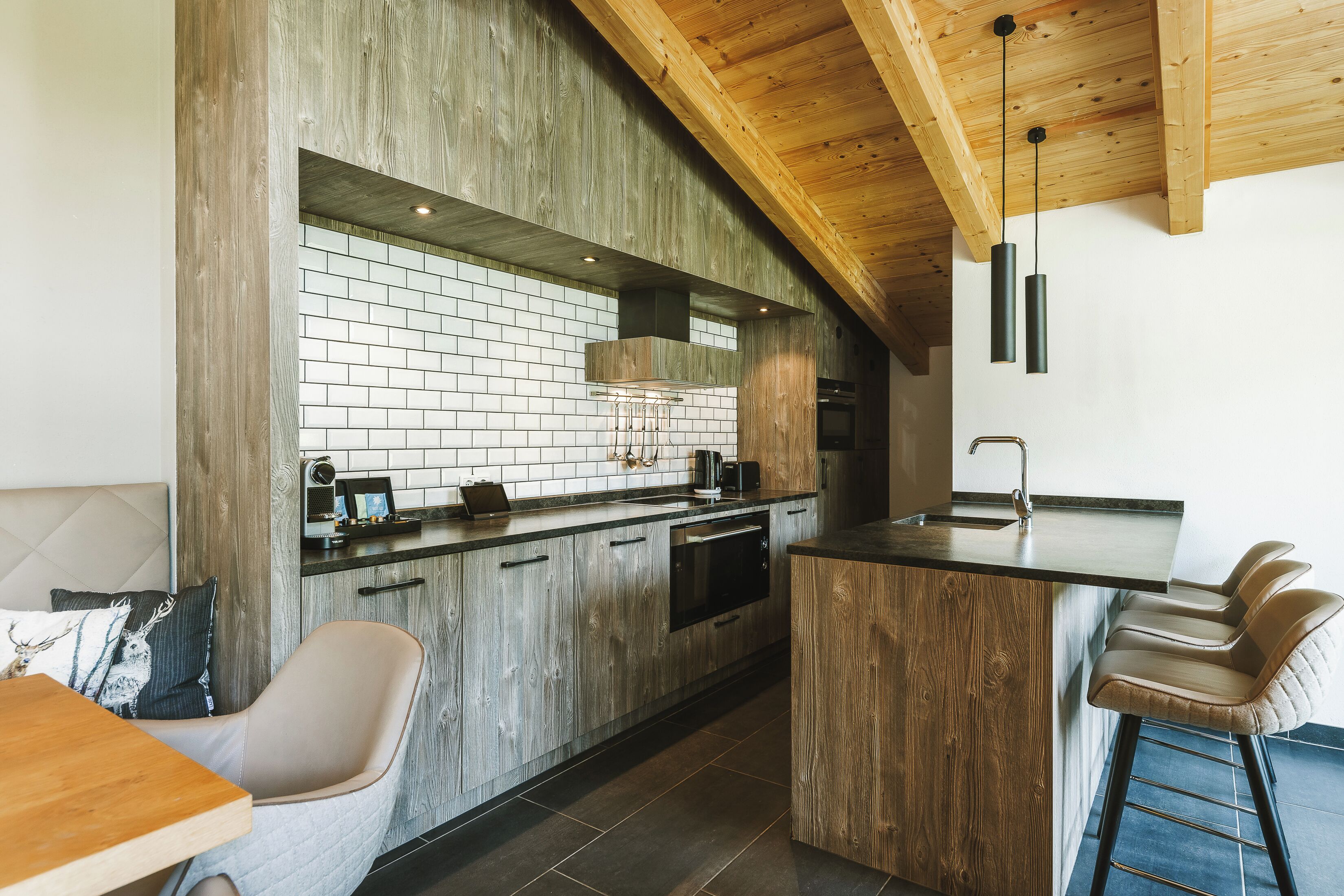 Cozinha moderna com armários de madeira, painel de fundo de tijolos e um espaço de bar com banquetas.