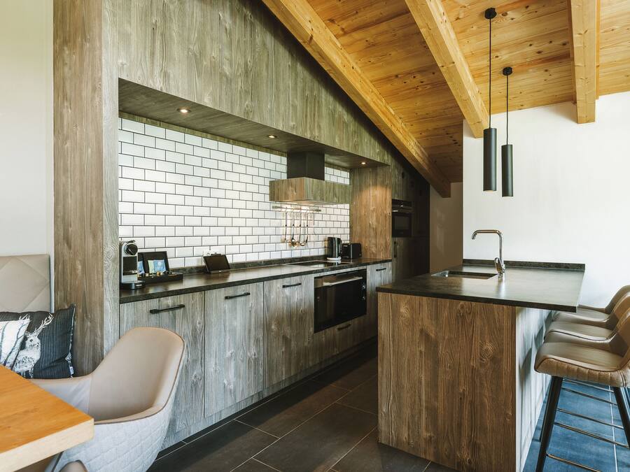 Cozinha moderna com armários de madeira, painel de fundo de tijolos e um espaço de bar com banquetas.