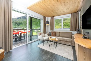 A modern living room with a sofa, a small round table, and a wooden ceiling. - AvenidA Panorama Suites Kaprun (Kaprun)