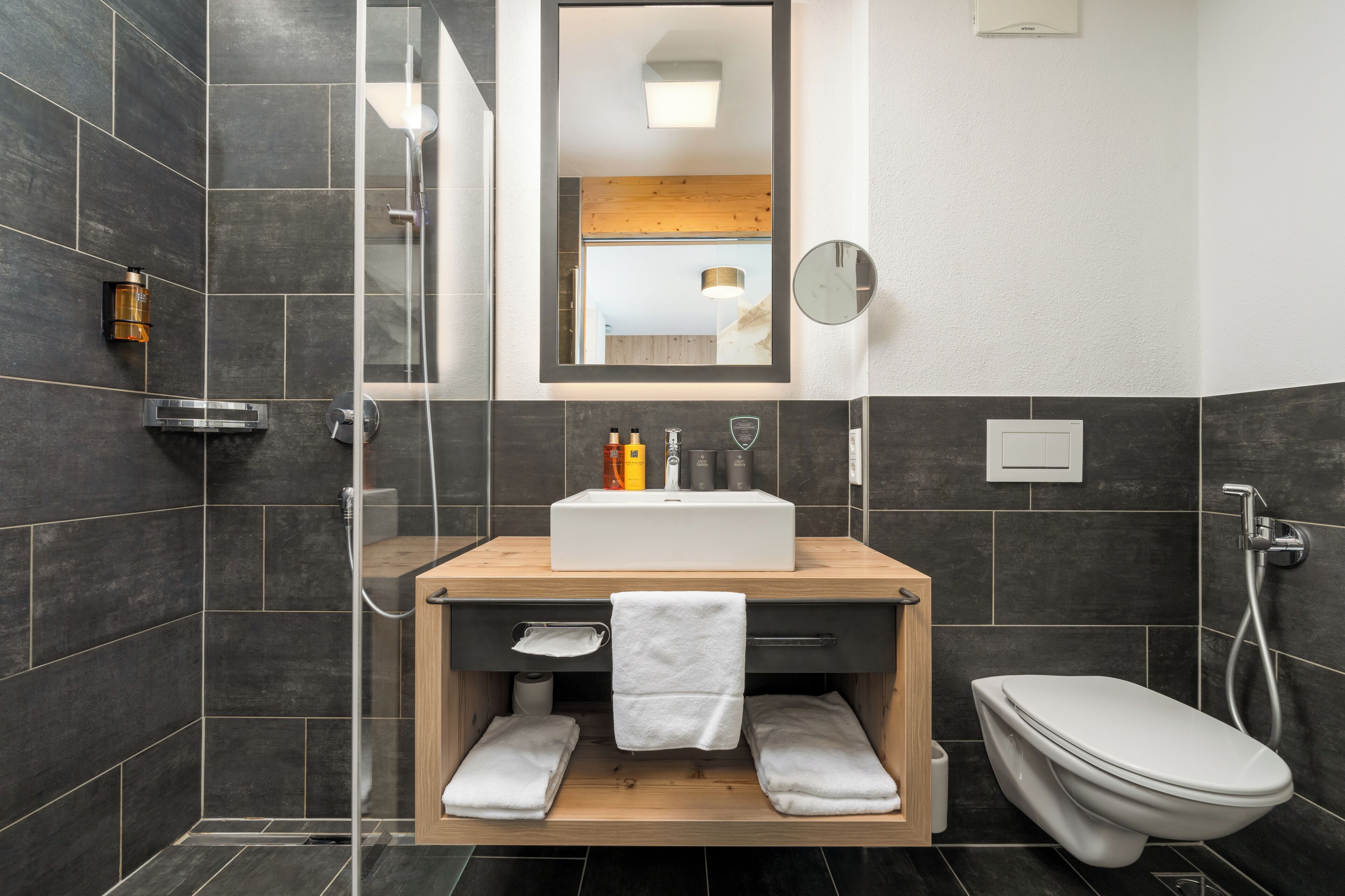 A modern bathroom with a wooden vanity, a white sink, and a toilet.