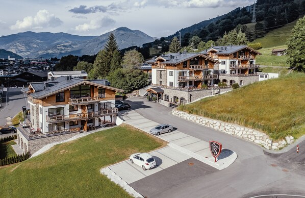A multi-story hotel with a stone facade, balconies, and a parking area. - AvenidA Panorama Suites Kaprun (Kaprun)