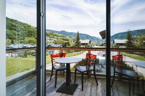 A balcony with a wooden floor, two round tables, and four red chairs. - AvenidA Panorama Suites Kaprun (Kaprun)