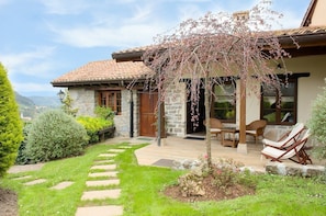 Ein Haus aus Stein mit Ziegeldach, ein Garten mit trittfesten Steinen und Sitzgelegenheiten im Freien.