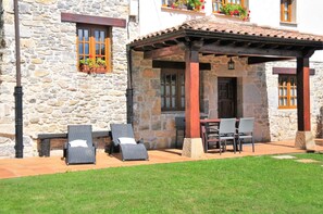 Un edificio de piedra con un patio cubierto y mobiliario para exteriores.