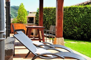 Un patio con una mesa, sillas y una parrilla.