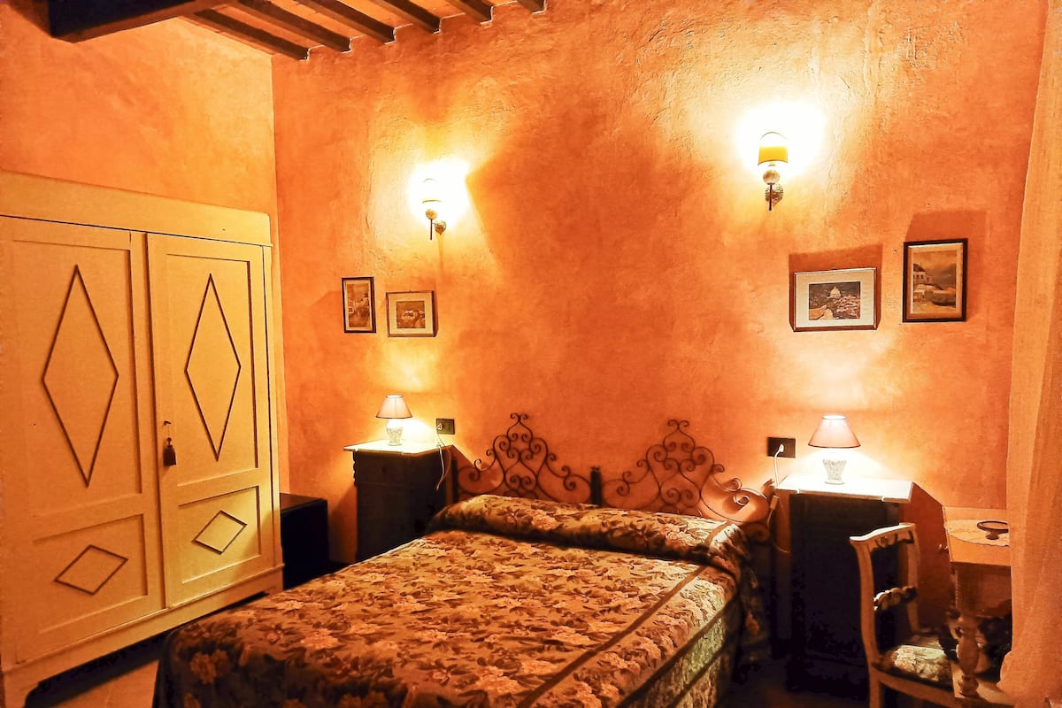 A bedroom with a bed, two bedside tables with lamps, a chair, and a wardrobe.