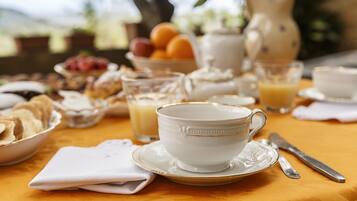 A breakfast table with a white cup, saucer, and a glass of orange juice.