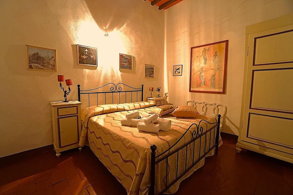 A bedroom with a bed, bedside tables, and wall art.