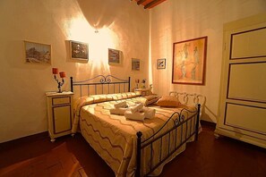 A bedroom with a bed, bedside tables, and wall art. - Locanda Etrusca (Bibbona)