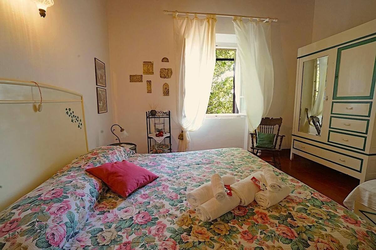 A bedroom with a bed, a dresser, a chair, and a window with curtains.