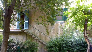 A stone staircase leading up to a building with green shutters, surrounded by greenery and trees. - Locanda Etrusca (Bibbona)