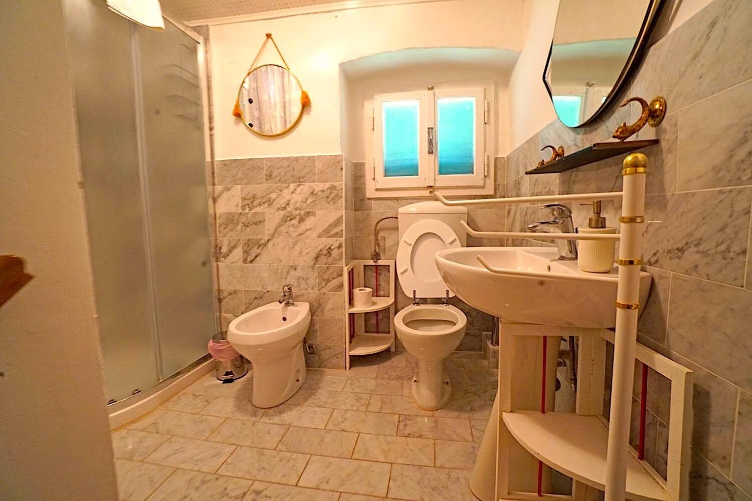 Ein Badezimmer mit Bidet, Toilette, Waschbecken und Spiegel.