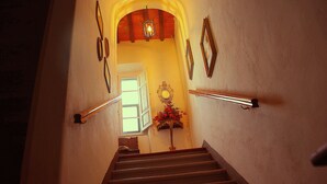 A staircase with wooden steps, a handrail on one side, and a mirror on the wall. - Locanda Etrusca (Bibbona)