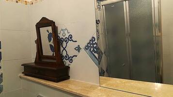 Casa de banho com espelho, cabine de duche e azulejos decorativos.