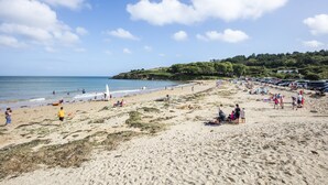 Ein Strand mit Menschen, einem sandigen Ufer und blauem Himmel.