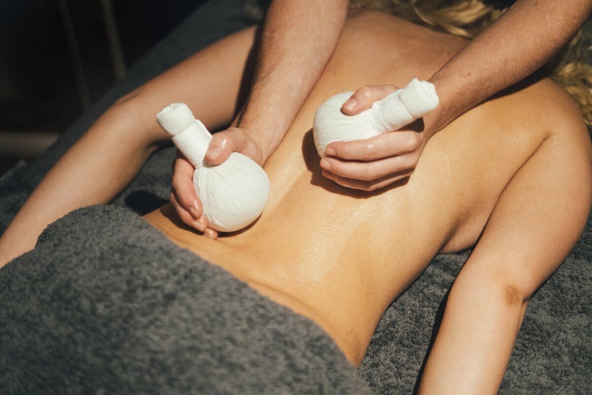A person receiving a massage with a towel covering their lower body.
