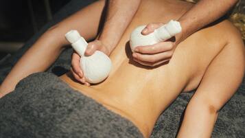 A person receiving a massage with a towel covering their lower body.