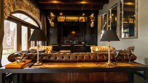 Un rincón acogedor con un sofá de cuero, dos lámparas y una mesa de madera.