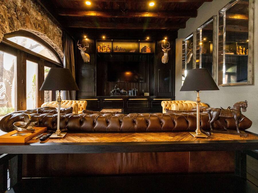 A cozy seating area with a leather sofa, two lamps, and a wooden table.