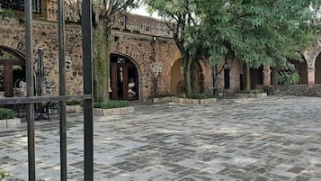 Un patio con suelo de piedra, puertas de arco y plantas en macetas.