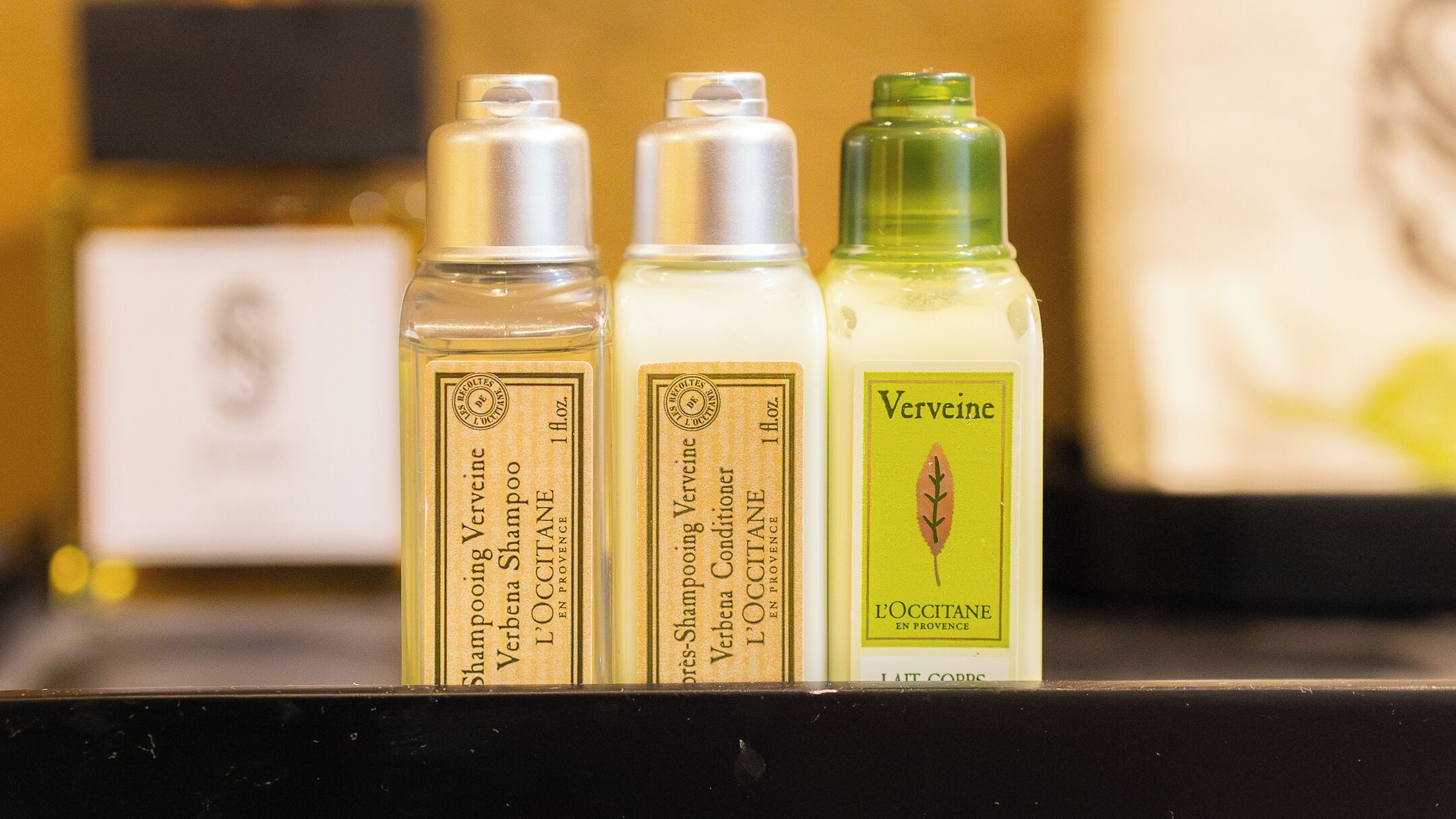 Three bottles of shampoo and conditioner on a shelf.