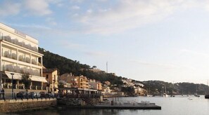 A waterfront hotel with a terrace, a dock, and boats in the background. - Hotel Brismar (Andraitx)