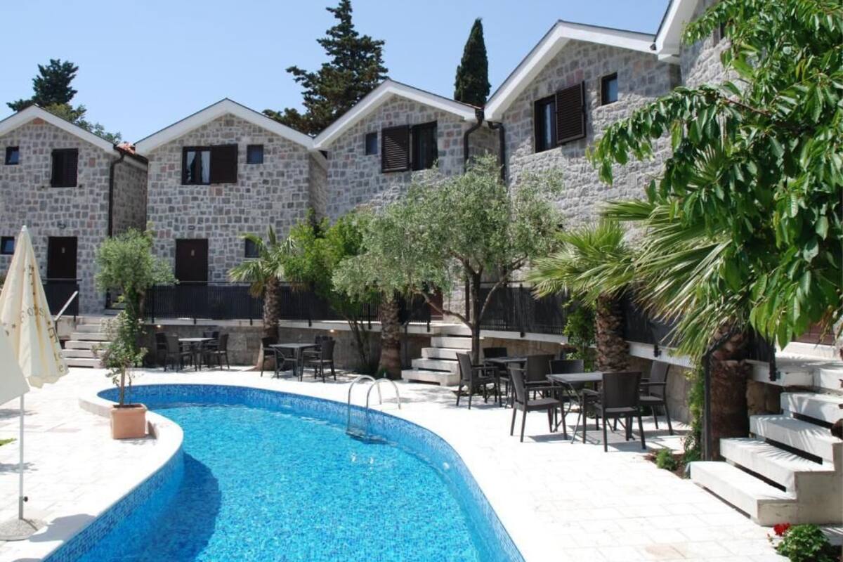 Zona de piscina con edificios de piedra, mobiliario de exterior y cielo despejado.