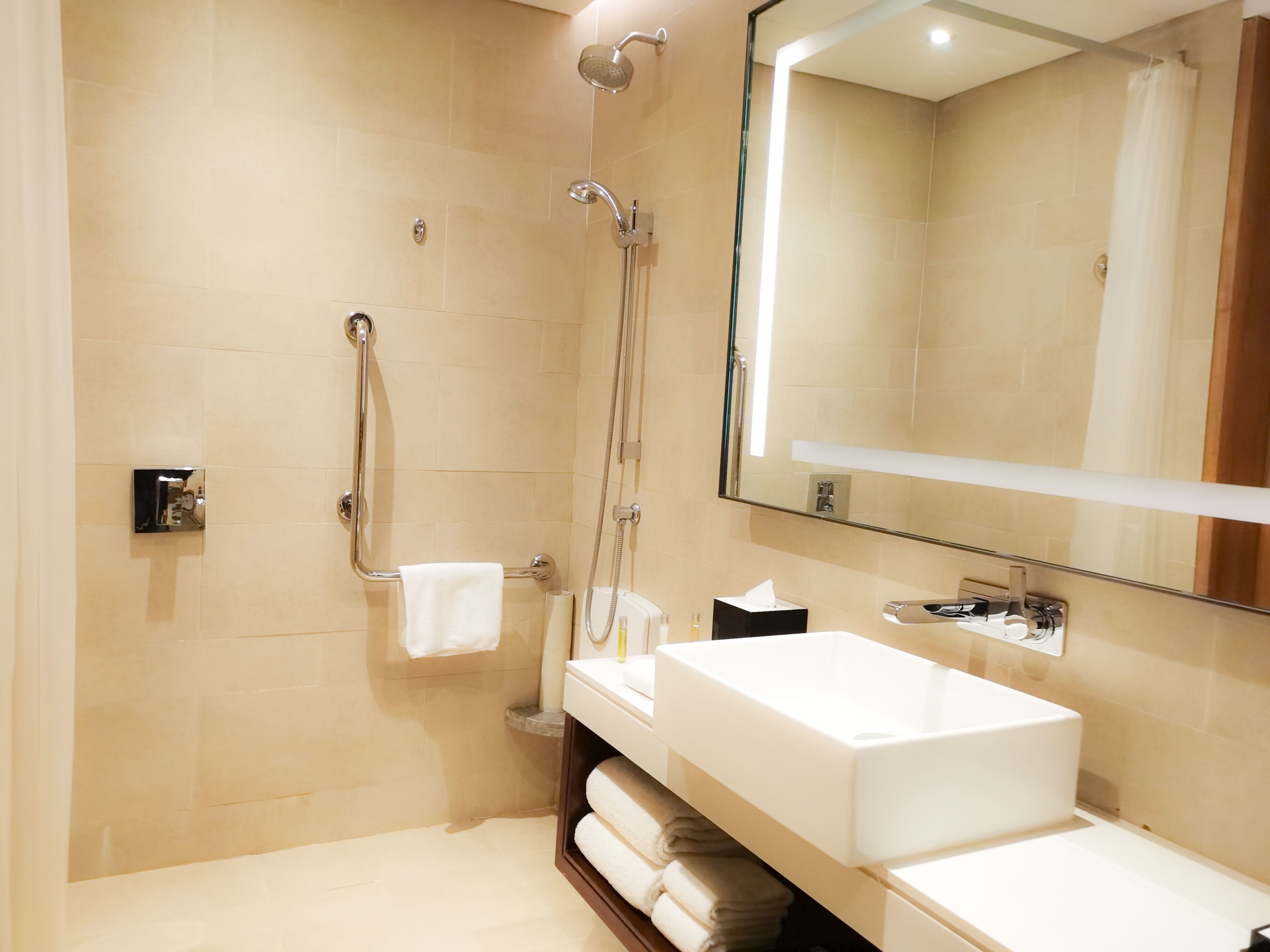 Un baño moderno con un espejo grande, un lavabo blanco y una zona de ducha.