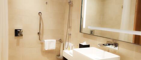 Un baño moderno con un espejo grande, un lavabo blanco y una zona de ducha.