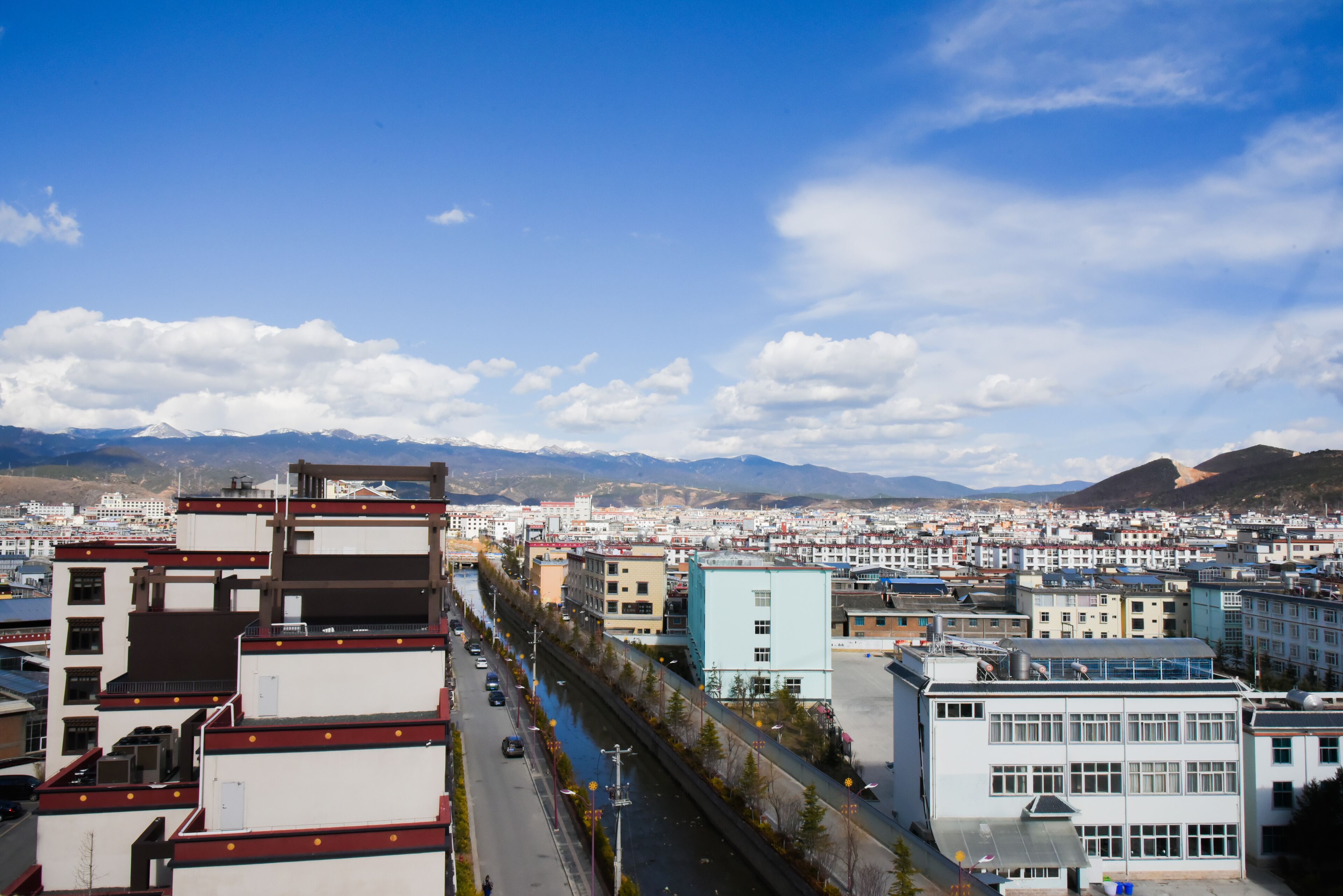 A cityscape with a river running through it, surrounded by mountains in the background.