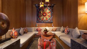 A modern interior with a wooden wall, a patterned tapestry, and a leather bag on a sofa. - Hilton Garden Inn Shangri-La (Deqin)