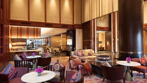 A spacious lobby with a high ceiling, a central seating area with sofas and tables, and a bar area with stools. - Hilton Garden Inn Shangri-La (Deqin)