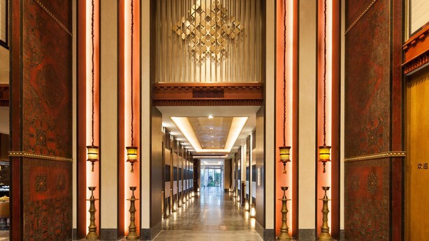 A long, well-lit hallway with ornate columns and a chandelier. - Hilton Garden Inn Shangri-La (Deqin)