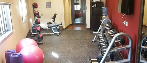 A gym with exercise equipment, a water dispenser, and a TV on the wall.