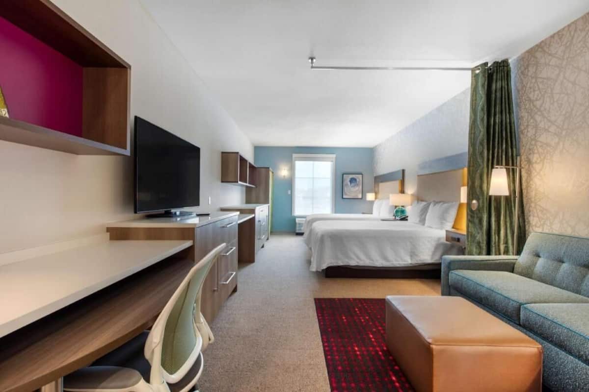 A hotel room with a bed, a desk, a television, a sofa, and a window.