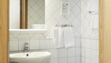 Une salle de bain avec un lavabo blanc, un miroir et des toilettes.