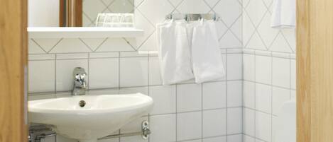 Baño con lavamanos, espejo y retrete blancos.
