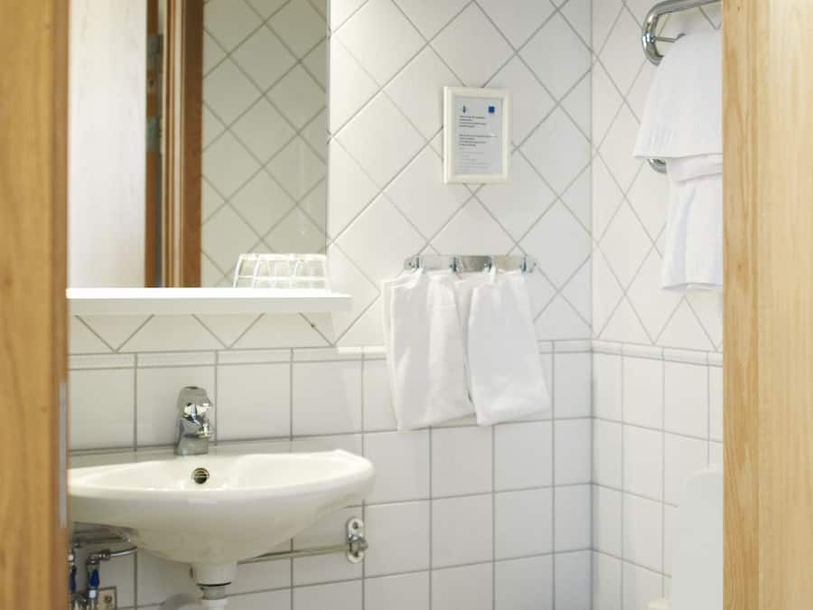 Baño con lavamanos, espejo y retrete blancos.