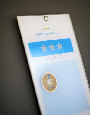A hotel rating badge with three stars and a gold circular badge with a blue and white emblem.