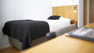 Et hotelværelse med seng, natbord og sengegavl i træ.