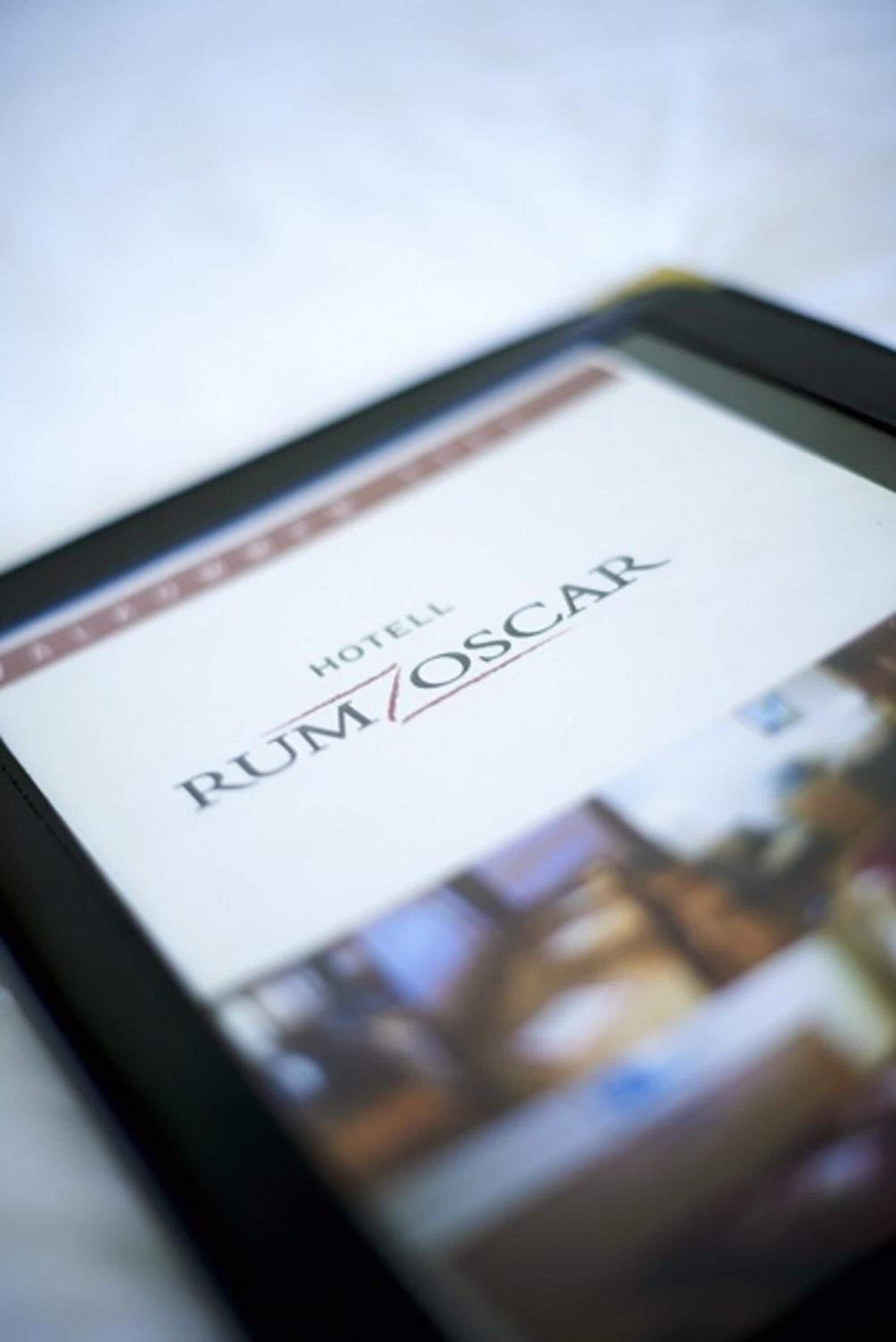 Una tableta mostrando el nombre de un hotel, 'HOTEL RUMOSCAR', con un fondo desenfocado.