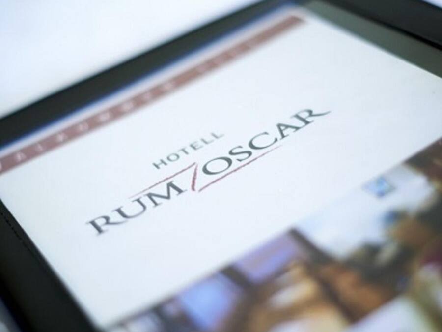 Una tableta mostrando el nombre de un hotel, 'HOTEL RUMOSCAR', con un fondo desenfocado.