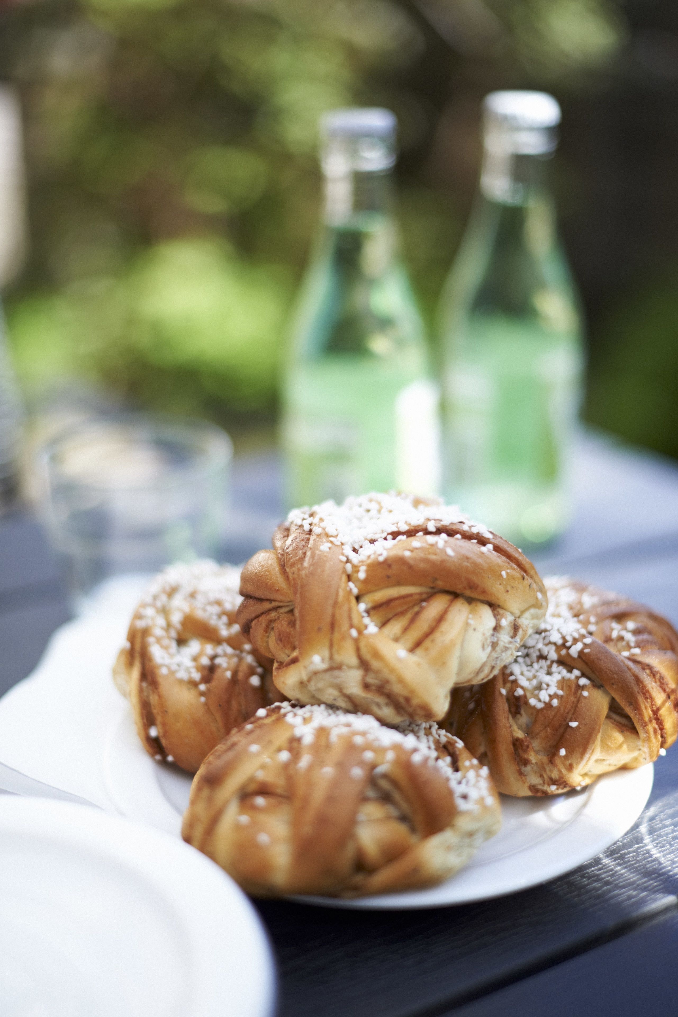 A plate of cinnamon rolls with sugar on a wooden table.
