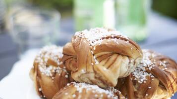 A plate of cinnamon rolls with sugar on a wooden table.