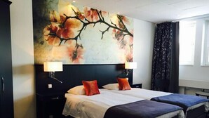 A hotel room with a large bed, two bedside tables, a nightstand, a window with curtains, and a floral wall mural. - Hotell Rum Oscar (Oskarshamn)